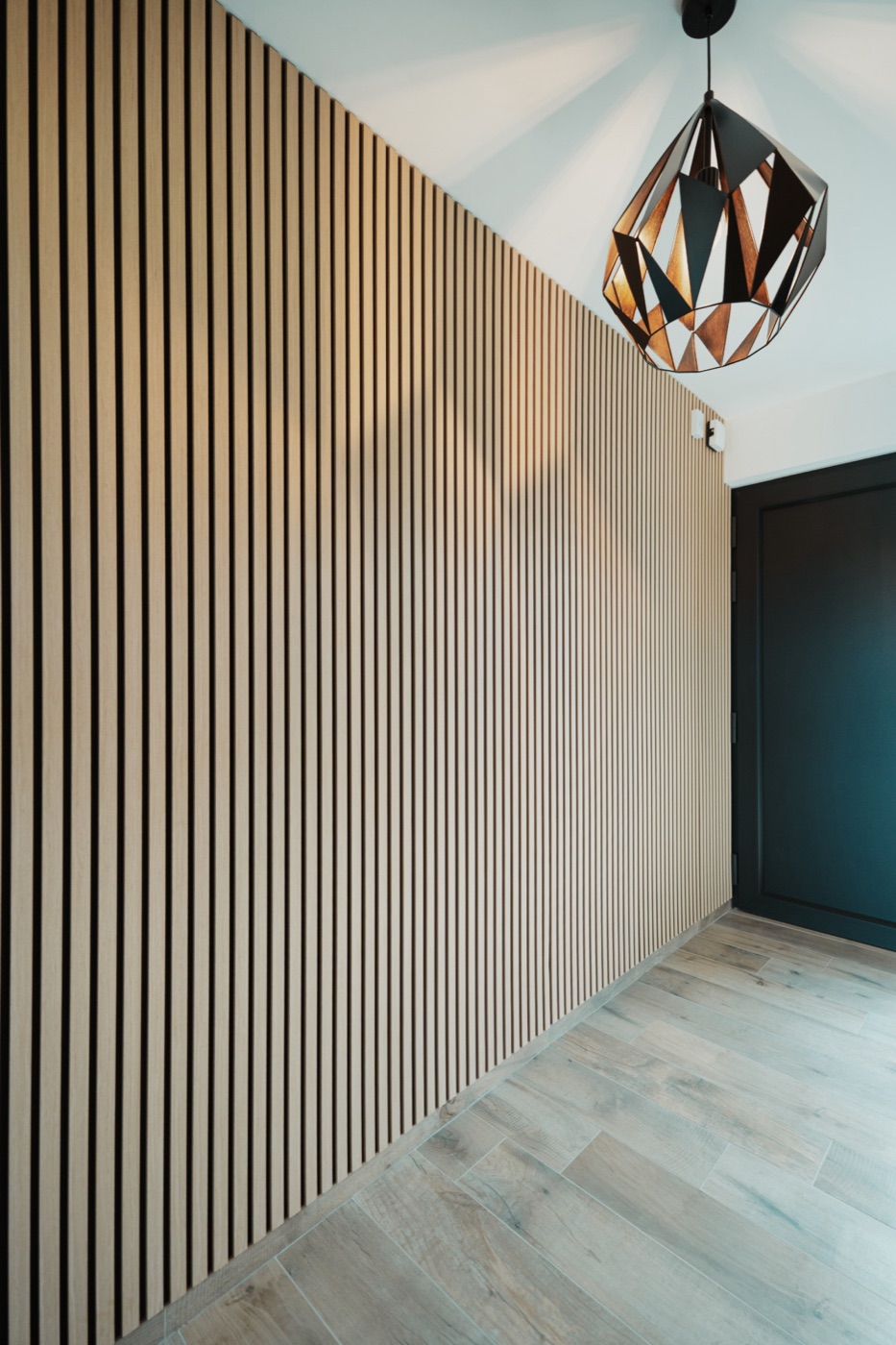 Mur en panneaux acoustiques bois chêne clair dans un hall d'entrée
